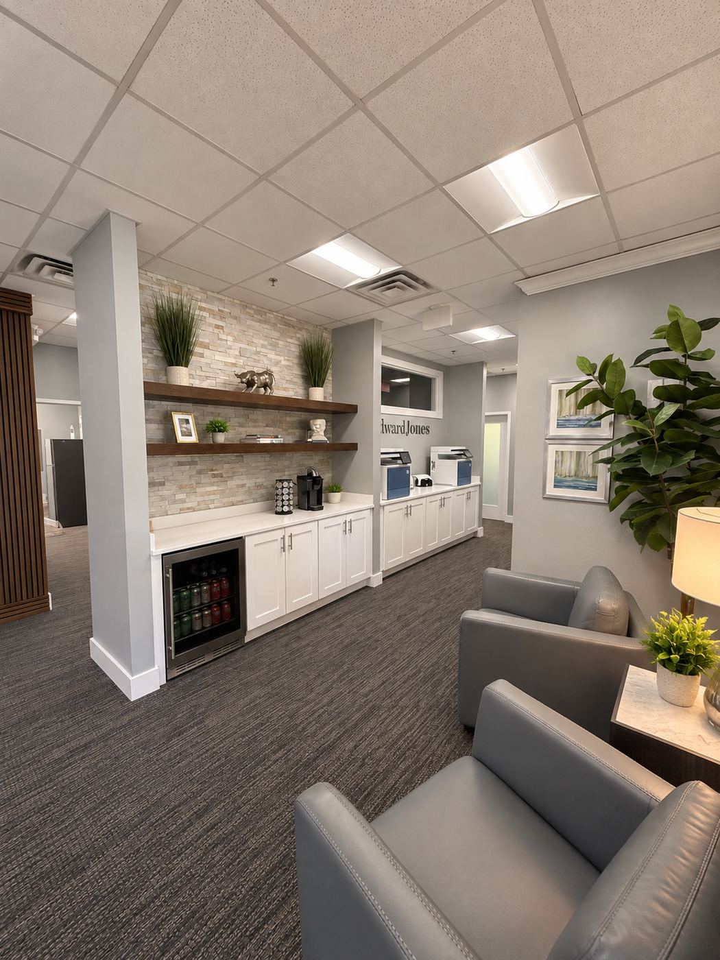 Finished commercial office build-out by Harrison Building Co — client lounge with a stone-faced coffee bar, floating walnut shelves, white shaker cabinetry and quartz counter