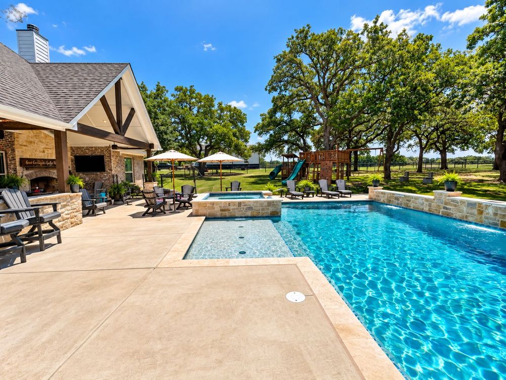 Custom gunite pool with raised spa and stone decking built in North Texas