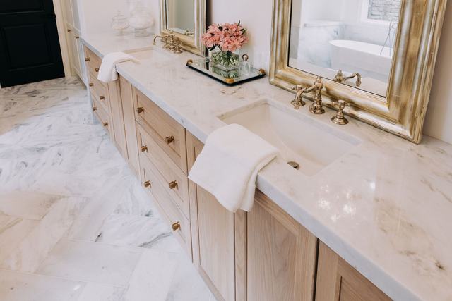 Double vanity in a primary bathroom remodel — white oak cabinetry, marble counters, and brass fixtures
