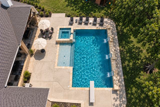 Aerial view of a custom pool and raised spa with travertine decking, built by Harrison Building Co in Denton County