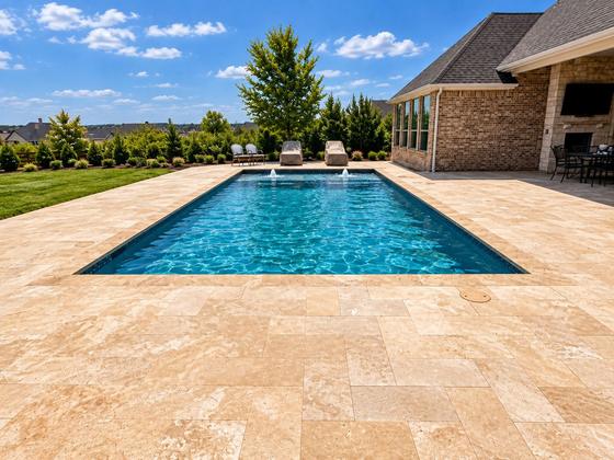 Rectangular pool with a wide travertine deck and loungers