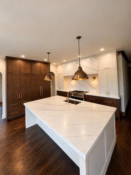 Kitchen remodel with a marble waterfall island, brass pendants and walnut pantry cabinetry