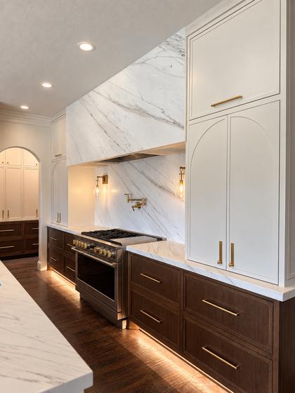 Kitchen range wall with a full-height marble slab surround, brass pot filler and walnut base cabinets