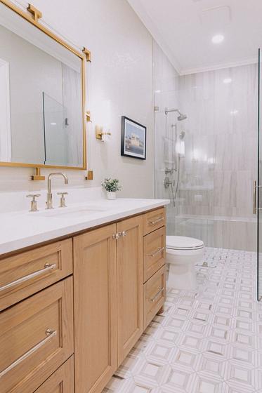 Primary bathroom remodel with a white oak vanity, marble shower surround and brass fixtures