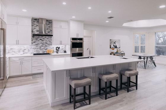 White kitchen remodel with a quartz island, bar seating and a full-height tile backsplash