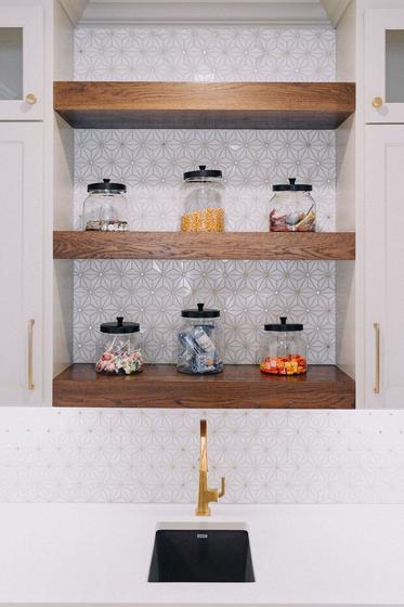 Beverage bar with stained floating shelves and brass faucet