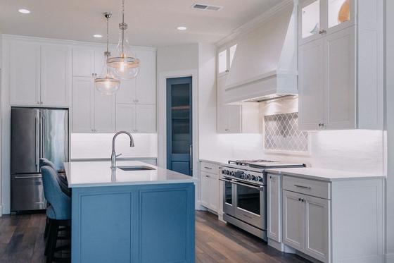 White kitchen remodel with a blue island and glass pendants