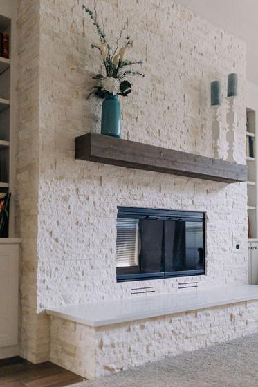 Whitewashed stone fireplace with stained timber mantel