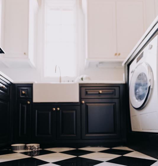 Laundry room remodel with black cabinetry, a farmhouse sink and a marble checkerboard floor
